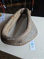 Full view of brown leather horse collar on tabletop