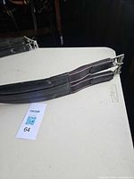 Full girth showing leather body, elastic ends, twin roller buckles, pink piping