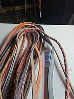 Bundle of assorted leather reins laid on table, tag visible