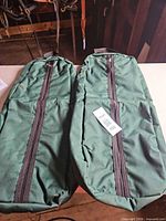 pair of green canvas tack bags side by side with zippers visible