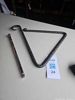 Triangular hanger and chrome rod on tabletop with lot tag visible