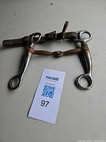 Overall view of Pelham curb horse bit, leather strap attached