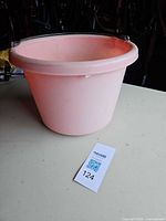 side view of pink plastic bucket showing overall form and rim chips