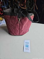 Front view of red canvas grooming tote with straps and key clip