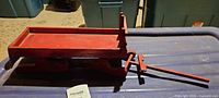 Side view of red wooden sled on storage bin