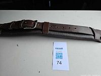 Overall view of the brown padded leather cinch showing length and buckle end