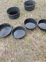Six black plastic tubs upright on ground