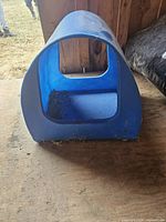 Front view of blue plastic pet house showing open entrance, dirty interior and scuffs