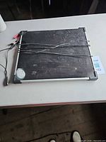 Front of aluminum-framed solar panel with cables laid across surface