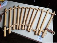 Full view showing twelve wooden dowels connected by rope with straps and hardware