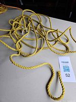 Coiled yellow rope on table with MaxSold lot card visible