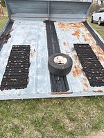 Top view of trailer deck showing rubber strips, keel rollers, rust, and loose wheel