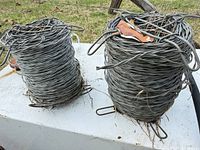 Two rolls of smooth galvanized steel fence wire on surface