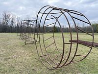 Three round steel hay feeder rings standing on field