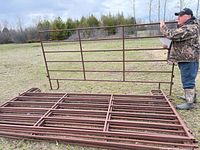 Stack of multiple steel corral panels with man holding one upright
