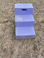 Front view of purple three-step stool on grass