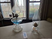 Both oil lamps side by side showing overall design, bases, burners, chimneys