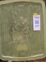Translucent green tote containing assorted metal hand tools and hardware pieces
