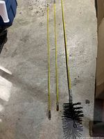 Brush head and three extension rods laid out on floor