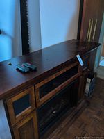 Front angled view of console showing top surface with two remotes and fireplace insert