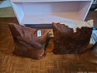 Two large square cowhide throw pillows, brown and white hair-on-hide