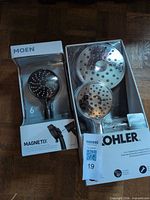 Front view of both boxed showerhead kits showing brands and chrome heads
