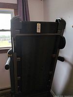 Treadmill folded upright, view of underside and frame