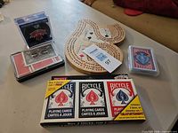 Overview of all items: 3-pack sealed cards, two loose decks in cases, wooden cribbage board, 2016 hockey puck in cube