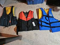 All three adult life jackets laid out showing colours, closures, and general wear