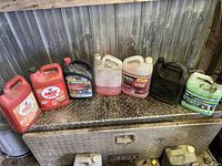 Nine assorted plastic fluid containers on metal chest