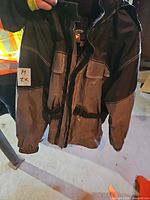 Black/gray synthetic shell parka with flap pockets and buckle straps