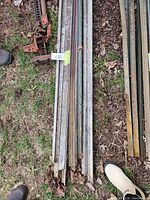 Bundle of galvanized and green-painted T-posts with red farm jack visible