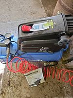 Compressor top view showing motor housing, red switch, tank, hose, manual