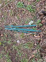 Four green steel fence posts lying on ground