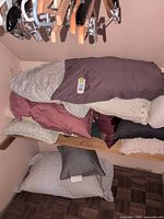 Stacked bed and throw pillows on shelf showing colors and tag