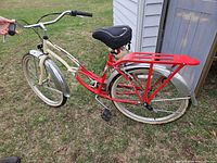 Full side view of red and cream Schwinn cruiser bicycle with 26-inch wheels, fenders and rack