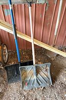 Full view of both shovels standing against wall