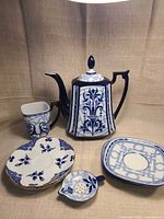 Full view of teapot, cup, three plates, strainer