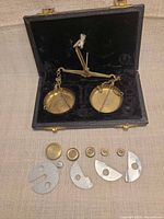 open case showing brass scale and pans, weights laid out