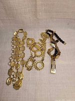 Three gold-tone chain accessories laid out