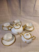 Full view of teapot, sugar bowl, four cups and saucers