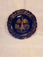 Front view of cobalt blue porcelain plate with gold Paris landmarks, scalloped and gilded rim.