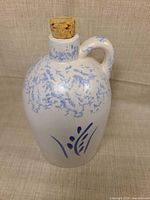 Front view of jug showing blue spatter glaze, floral motif, cork in place