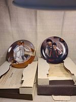 Both Rockwell plates in their open boxes with certificates visible