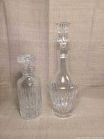 Front view of both decanters showing size difference and cut patterns