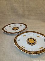Two matching porcelain plates with navy and gold Bacchus design