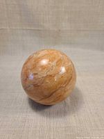 Full view of polished marble sphere on neutral background