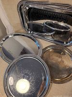 All five trays displayed; shows mix of rectangular and round forms, engraving details and beaded rims