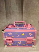 Front view showing butterfly and floral panels, pink frame, handle and latches