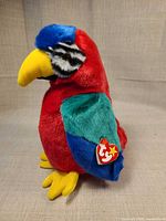 Left side profile of multicolor Ty parrot plush showing heart swing tag